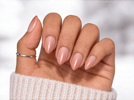 Hand held with palm facing viewer showing nude-to-pink gradient ombre press-on nails in a sophisticated short almond shape.