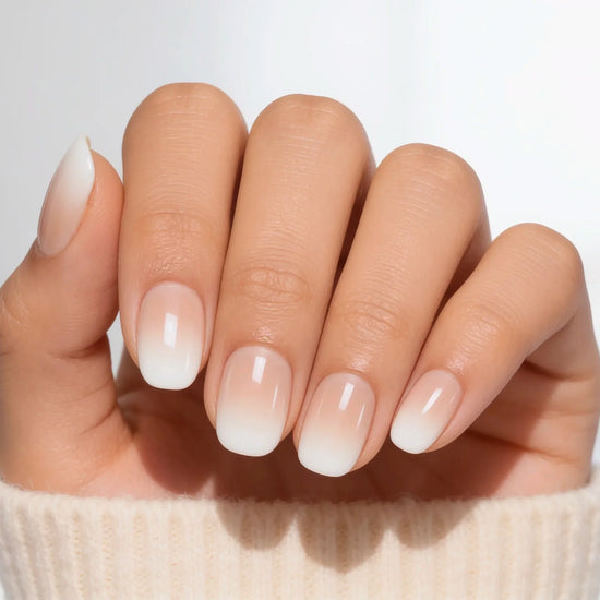 A palm-view shot of classic nude-to-white "boomer" or baby boomer style ombre press-on nails in a crisp extra short round shape.