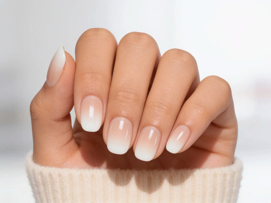 A palm-view shot of classic nude-to-white "boomer" or baby boomer style ombre press-on nails in a crisp extra short round shape.