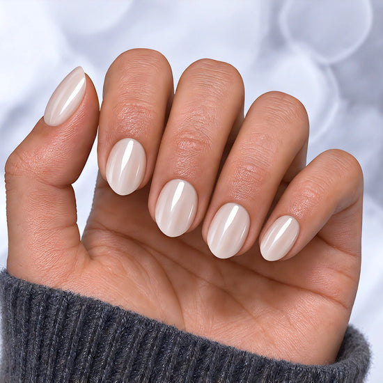 A palm-forward shot showing pearlescent white chrome extra short almond press-on nails with a clean, ethereal iridescent glow.