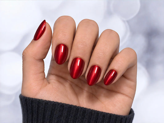 A palm-facing view of ruby red velvet chrome short almond press-on nails, showing the deep 3D cat-eye texture and reflective shine.