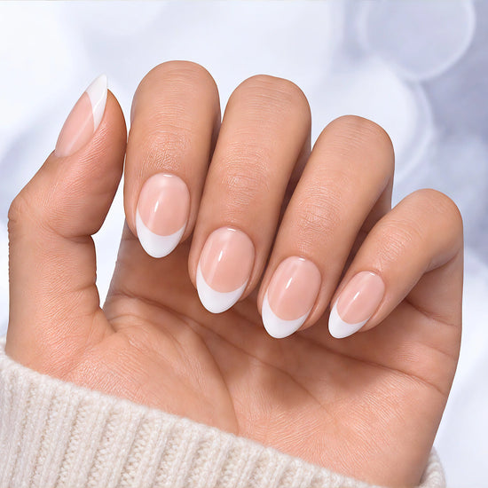 Palm-facing view of classic French tip press-on nails in soft pink with a glossy short almond shape and white tips.