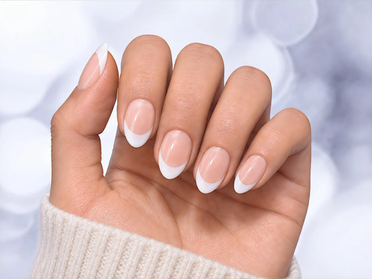 Palm-facing view of classic French tip press-on nails in soft pink with a glossy short almond shape and white tips.