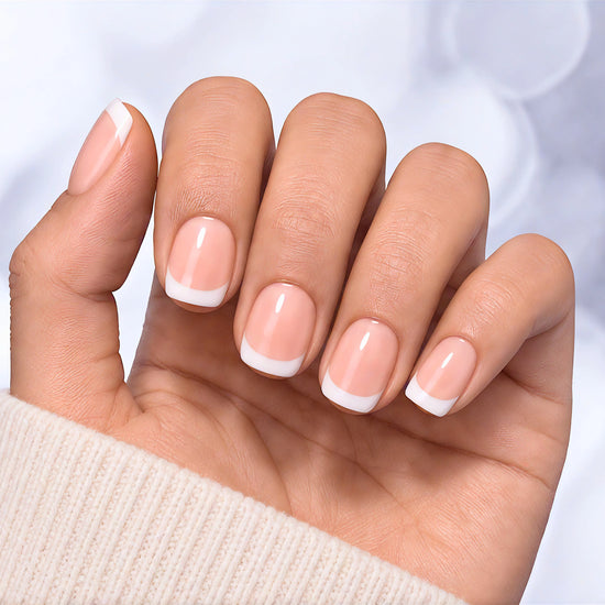 Relaxed hand pose showing soft pink glossy short square press-on nails with a clean, traditional French tip manicure.