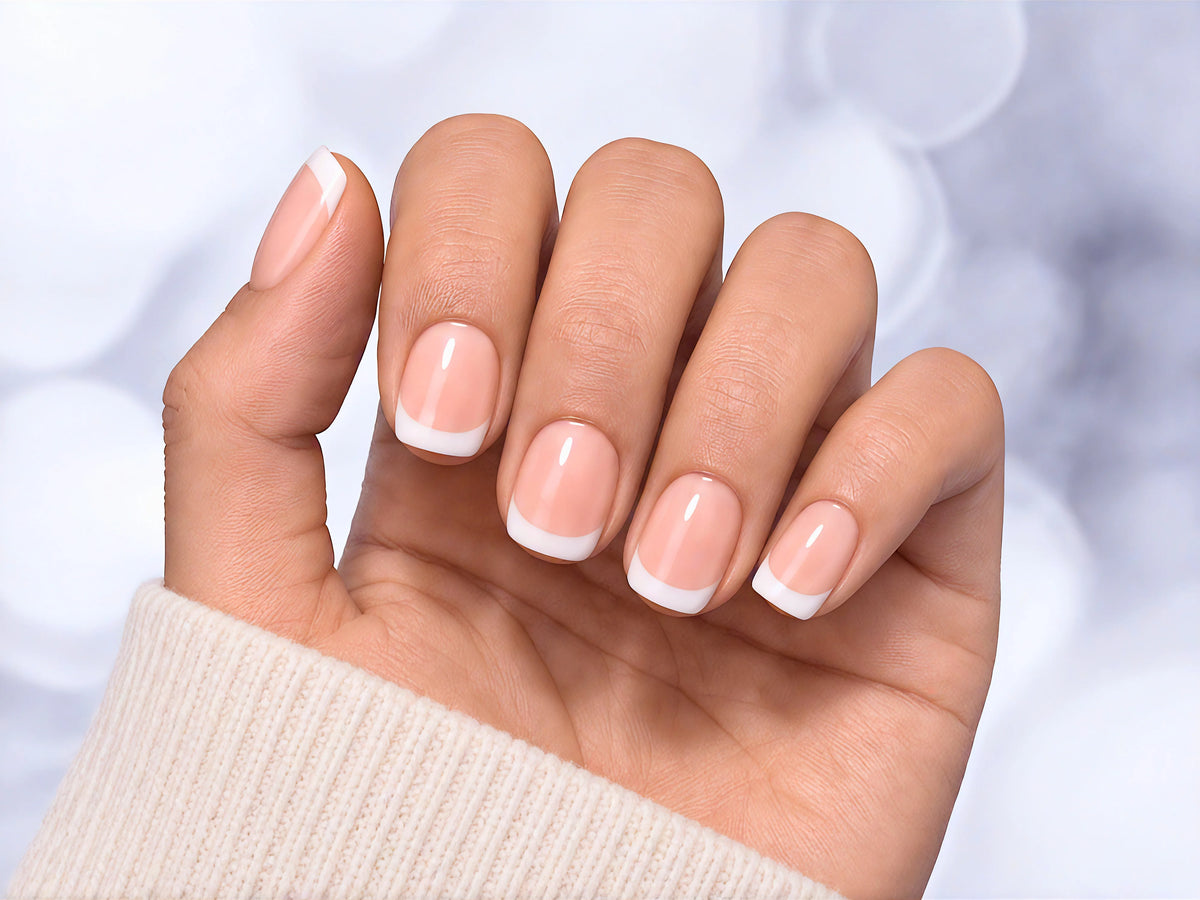 Relaxed hand pose showing soft pink glossy short square press-on nails with a clean, traditional French tip manicure.