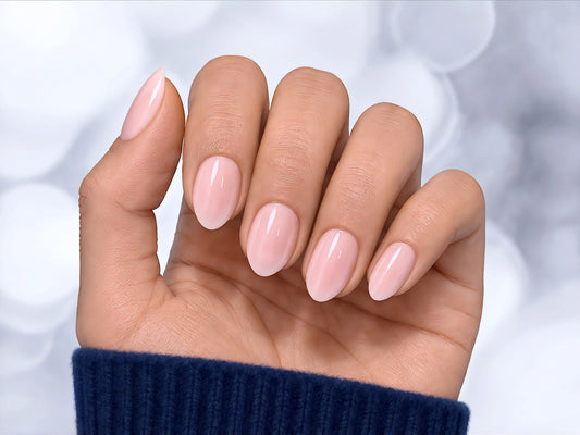 Palm-forward shot of sheer soft pink press-on nails in a short almond shape, emphasizing the natural, translucent "your nails but better" look.